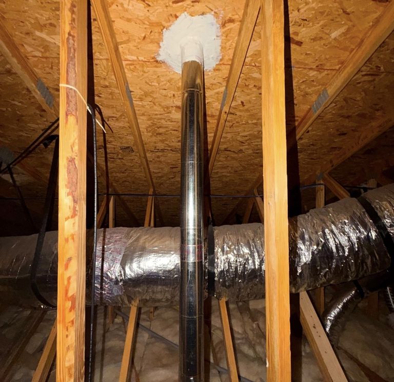 New rigid metal dryer vent pipe running up through an attic to the roof